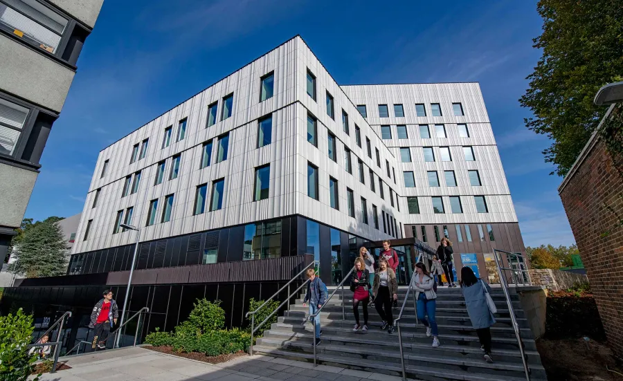 Students outside modern campus building on a sunny day.