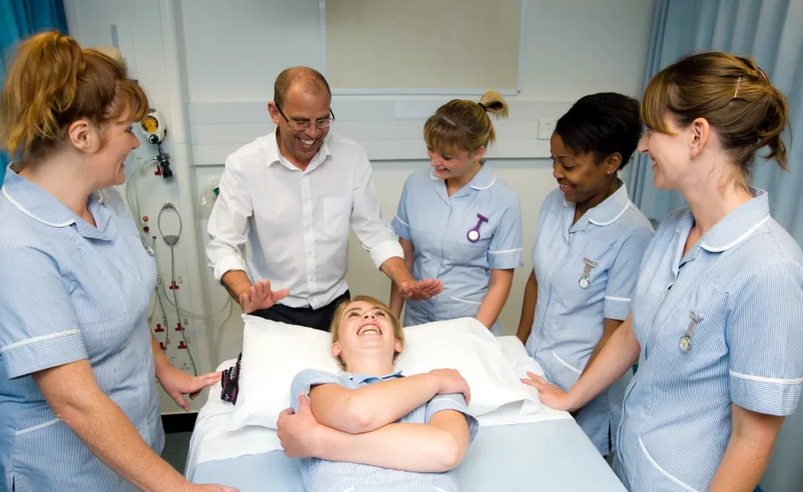 Nursing students gathered around a bed during a practical. 