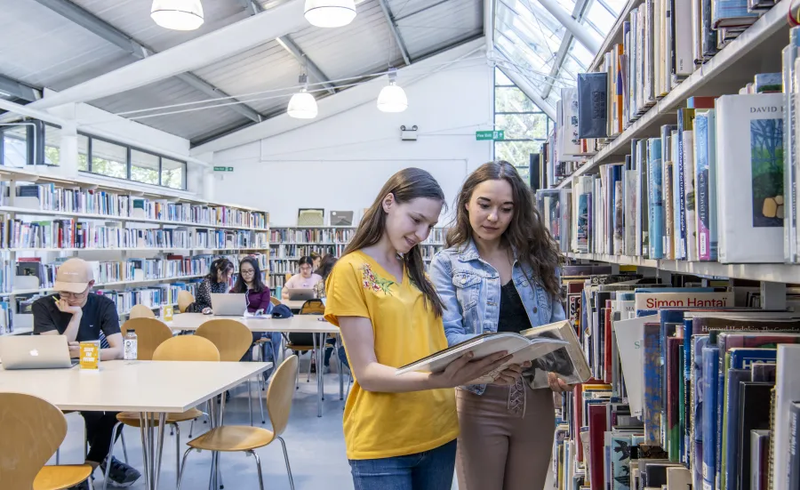 Students looking at books in university library