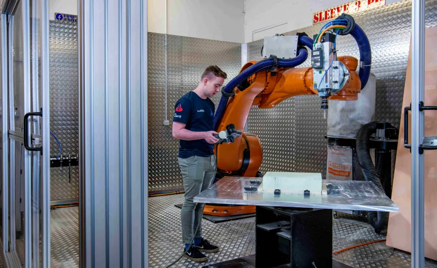 A student uses the robot arm in the engineering design and manufacturing centre