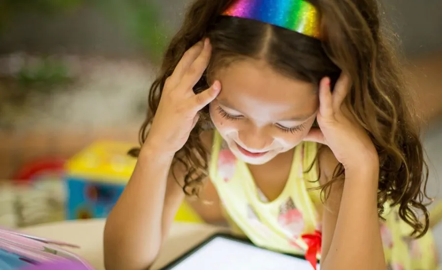 A young girl studies a tablet screen at a table