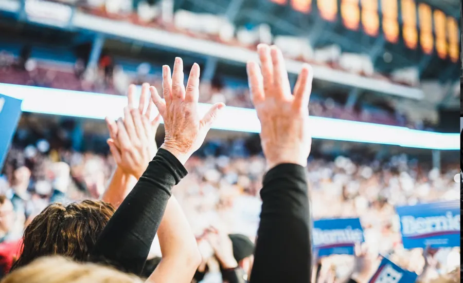 Audience members with their hands up at an American political rally