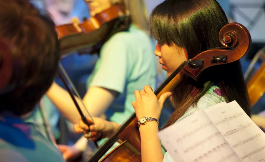 A student playing cello as part of the ƱAPP_ĿͲƱ-ٷϷ, University Symphony Orchestra.