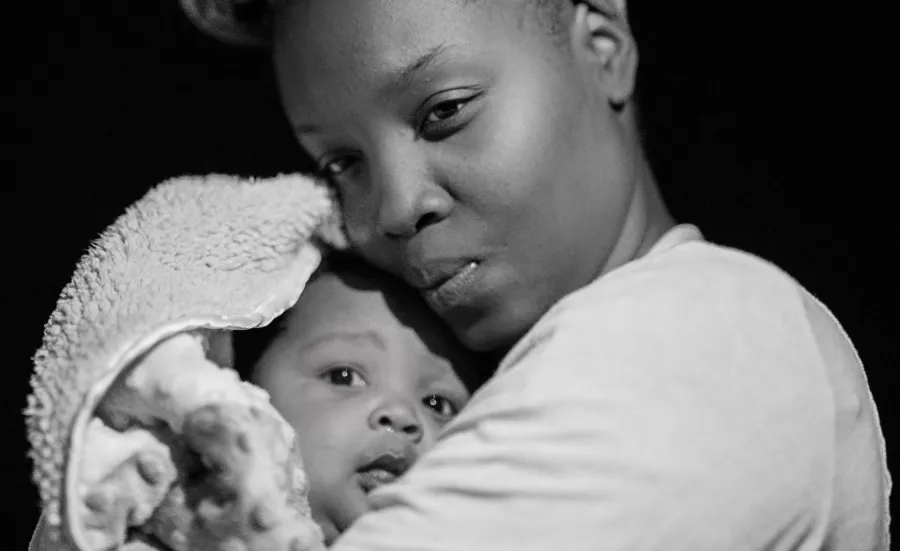 Black and white image of a mother holding her young baby close.