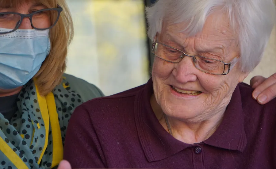 Elderly grey-haired woman with a masked carer