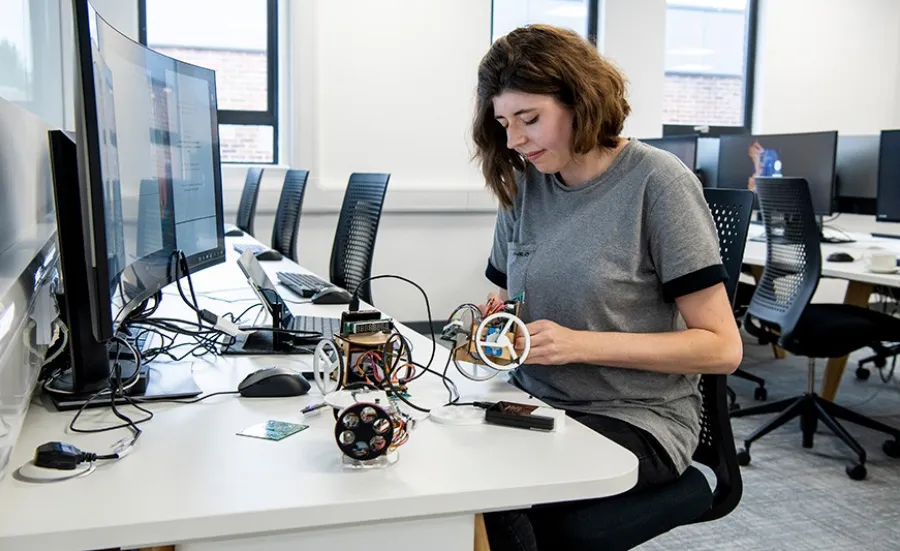 A researcher at a desk with computers and electronic equipment