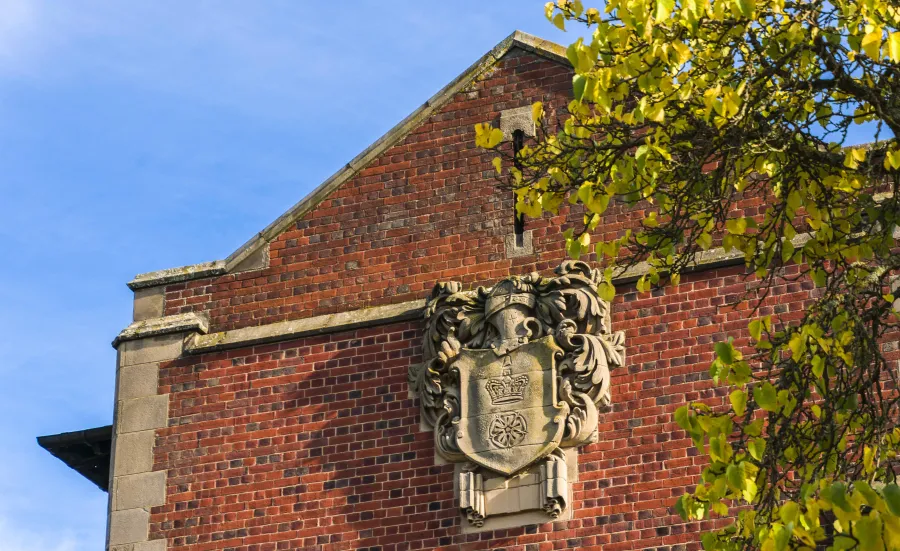 An old stone version of the University of ƱAPP_ĿͲƱ-ٷϷ, coat of arms, affixed to the side of Hartley Library.