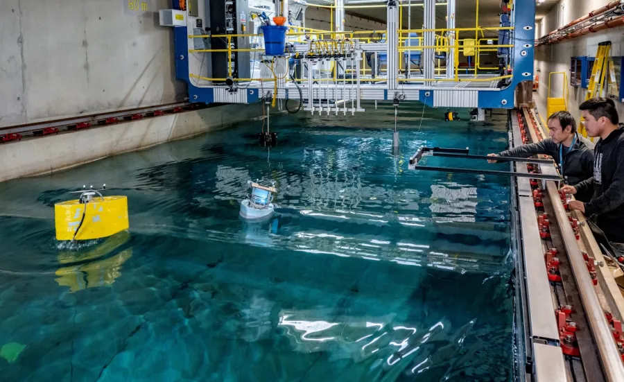 A student uses the 138m towing tank to investigates a buoy's hydrodynamic performance while a researcher offers advice