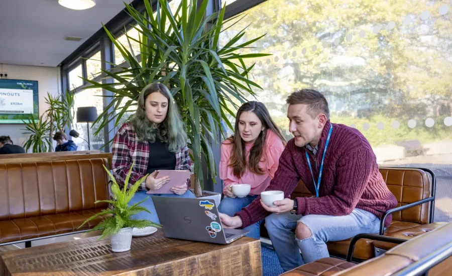 3 students from the Accessibility Allies team sitting in the caf at Highfield Campus, gathered around a laptop in discussion.