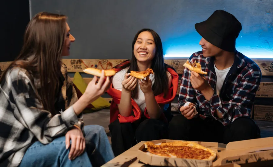 Three teenagers eating takeaway pizza