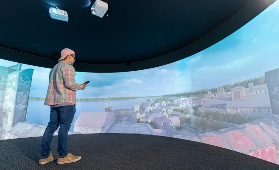 A person stands in our Igloo Immersive Environment facility, interacting with immersive content via a handheld device