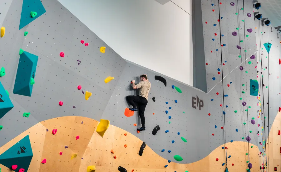 A climber climbing up ƱAPP_ĿͲƱ-ٷϷ, University's indoor climbing wall