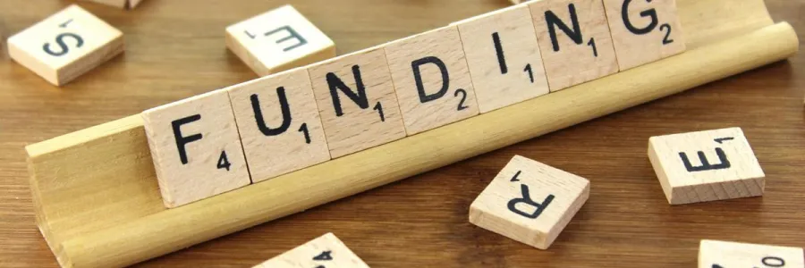 Wooden tiles from a game spelling out the word funding