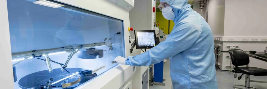 A researcher in a cleanroom suit uses a tool in the nanofabrication cleanroom, part of the chemical mechanical polishing process