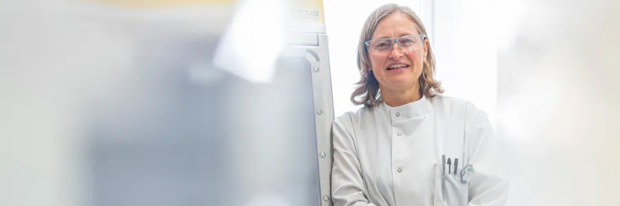 Scientist smiling next to lab equipment