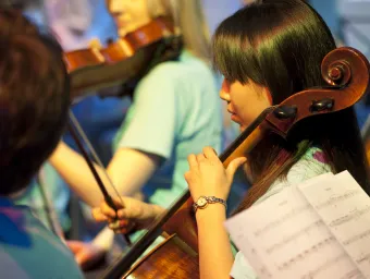 A student playing cello as part of the ƱAPP_ĿͲƱ-ٷϷ, University Symphony Orchestra.