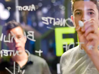 A man writing ideas on a glass wall with a marker pen