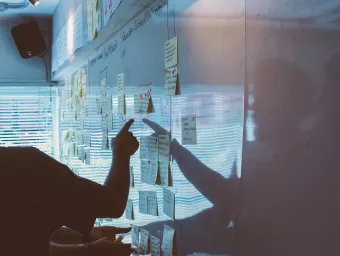 Unsplash image of post-its on a white board, a meeting participant points to a note