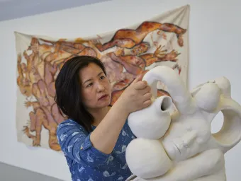 An artist manoeuvres an elaborate sculpture into position inside an art gallery