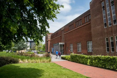 Exterior shot of academic building, trees and grass on a sunny day.