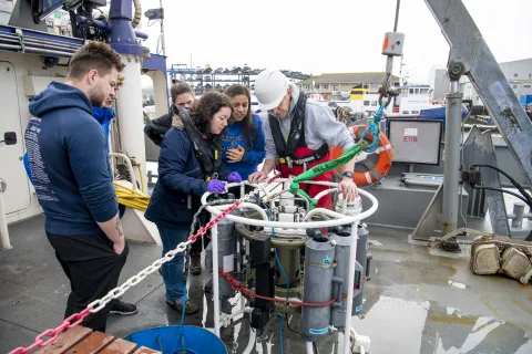 Students gathered around some tanks on the deck of the Callista ship