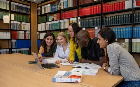 Students huddle around laptop in the library law collection