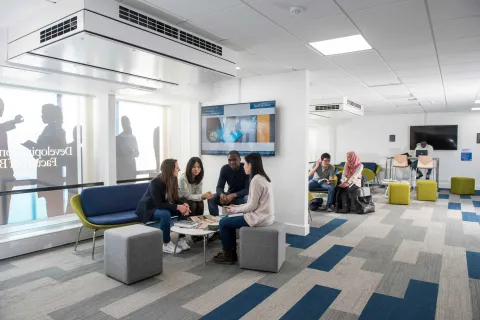 A small group of students sit and chat in a corner of the Business School study space.