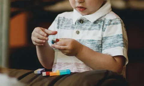 A child is absorbed in playing with brightly coloured building bricks