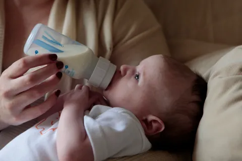 A mother feeds her baby from a bottle