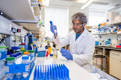 Professor Nullin Divecha working at a lab bench, surrounded by various containers and equipment.