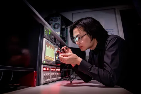 Researcher testing an integrated circuit attached to a computer and display screens