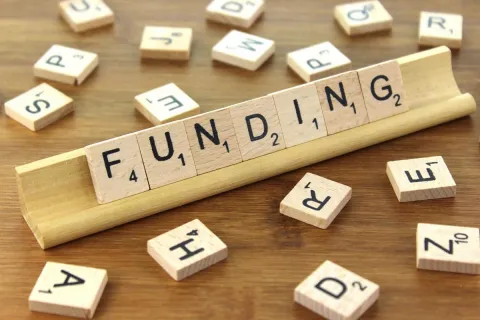 Wooden tiles from a game spelling out the word funding