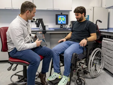 a researcher demonstrating the real-world impact of pressure sensing technology to a member of the group