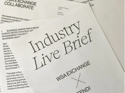 A report is printed on white paper and the pages are scattered, overlapping each other. The top page has the text 'Industry Live Brief. WSA Exchange X Fendi.