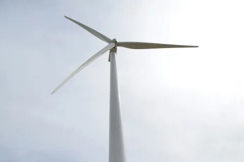 Wind turbine under cloudy sky.