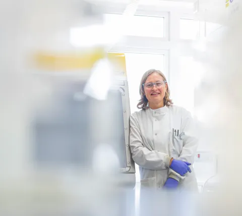 Scientist smiling next to lab equipment