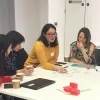 Teachers and advisers writing notes on flip chart sheets at table