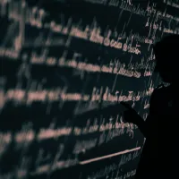 Stock image of a researcher's silhouette set against a wall projection of written language.