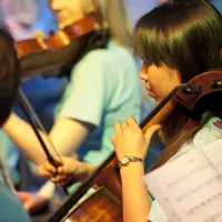 A student playing cello as part of the ƱAPP_ĿͲƱ-ٷϷ, University Symphony Orchestra.