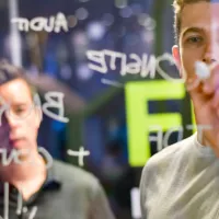 A man writing ideas on a glass wall with a marker pen