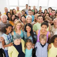 A stock photo of a large group of people of all ages, genders and ethnicities smiling up at the camera.