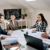 Group of 4 people talking around a work table