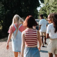 Teenagers walking down a sunny country lane away from the camera