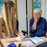 2 women sitting at a computer desk